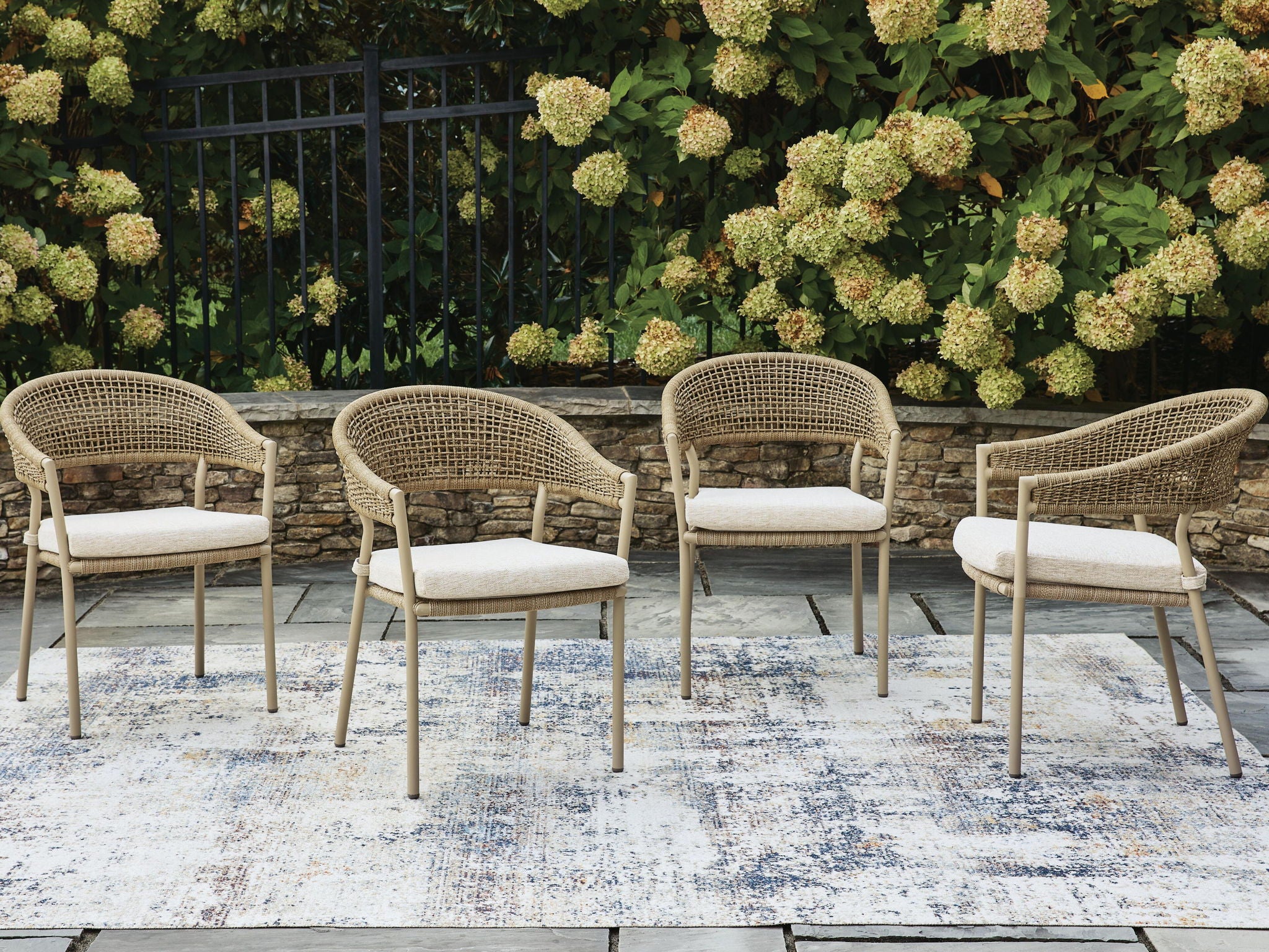 Set of 4 beige woven arm chairs with upholstered seat cushions, side-by-side view.