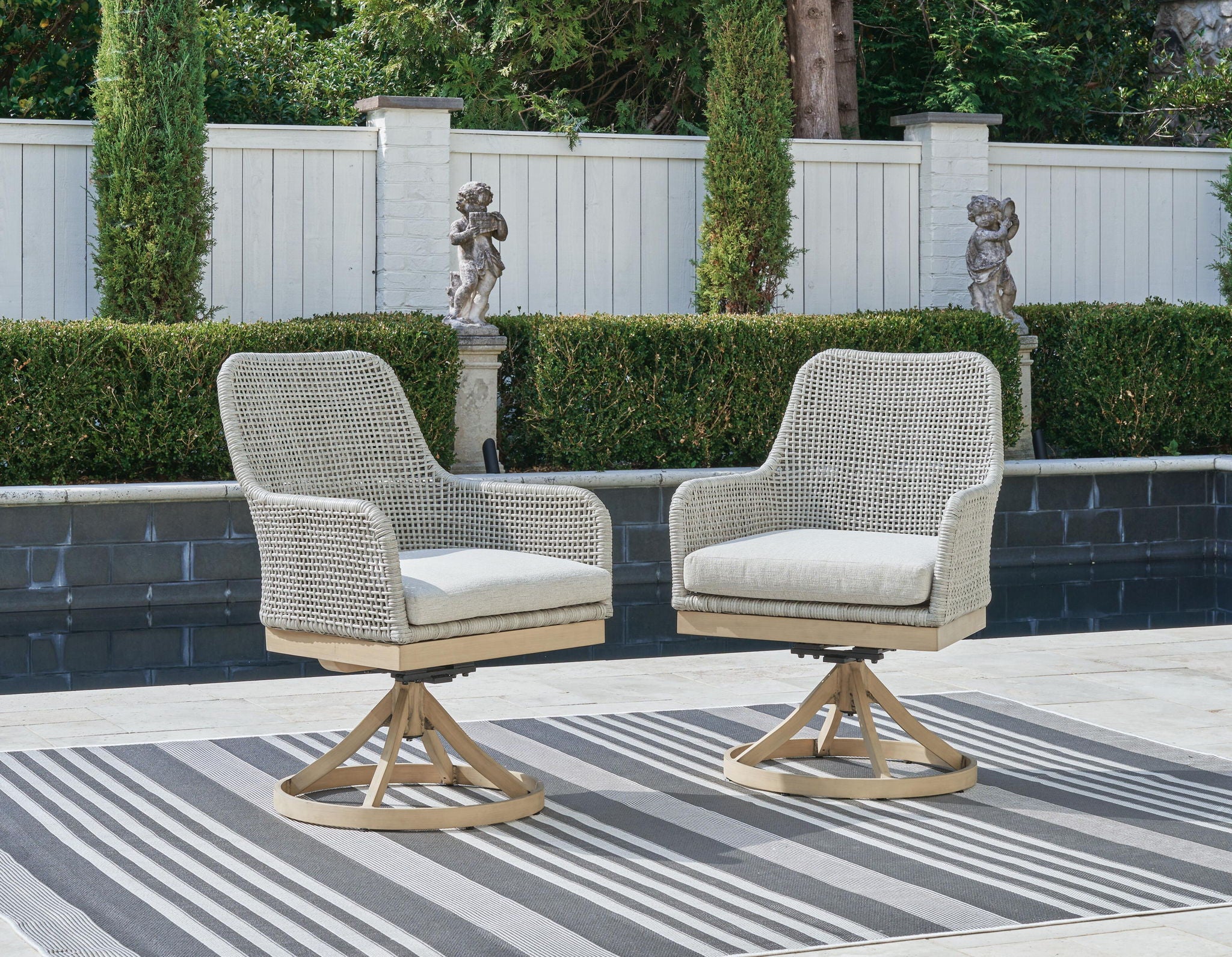 Pair of gray swivel patio chairs with white seat cushions and cross-brace base