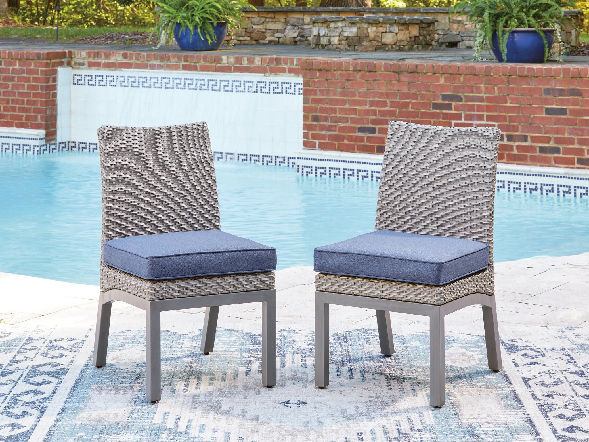 Set of 2 outdoor side chairs with blue cushions, gray woven backs, and tapered legs