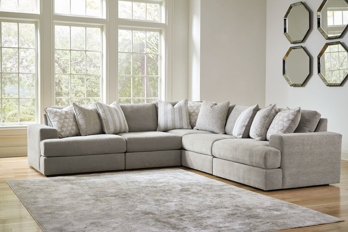 Light gray sectional sofa with chaise arm and multiple throw pillows in neutral tones.