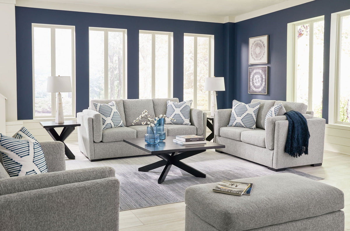 Gray living room sofa set with armchairs, patterned pillows, and a round ottoman
