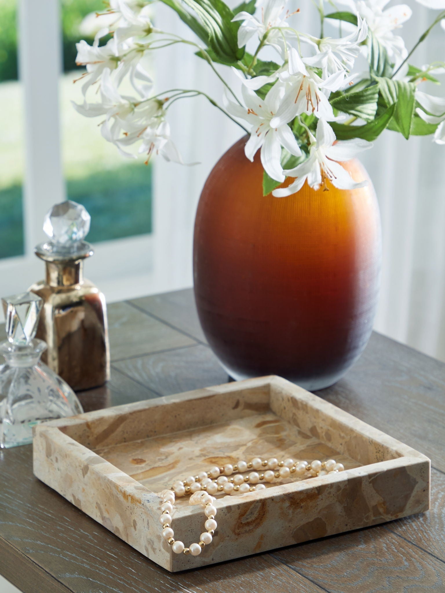 Light beige marble square tray on tabletop, holding white pearl bracelet
