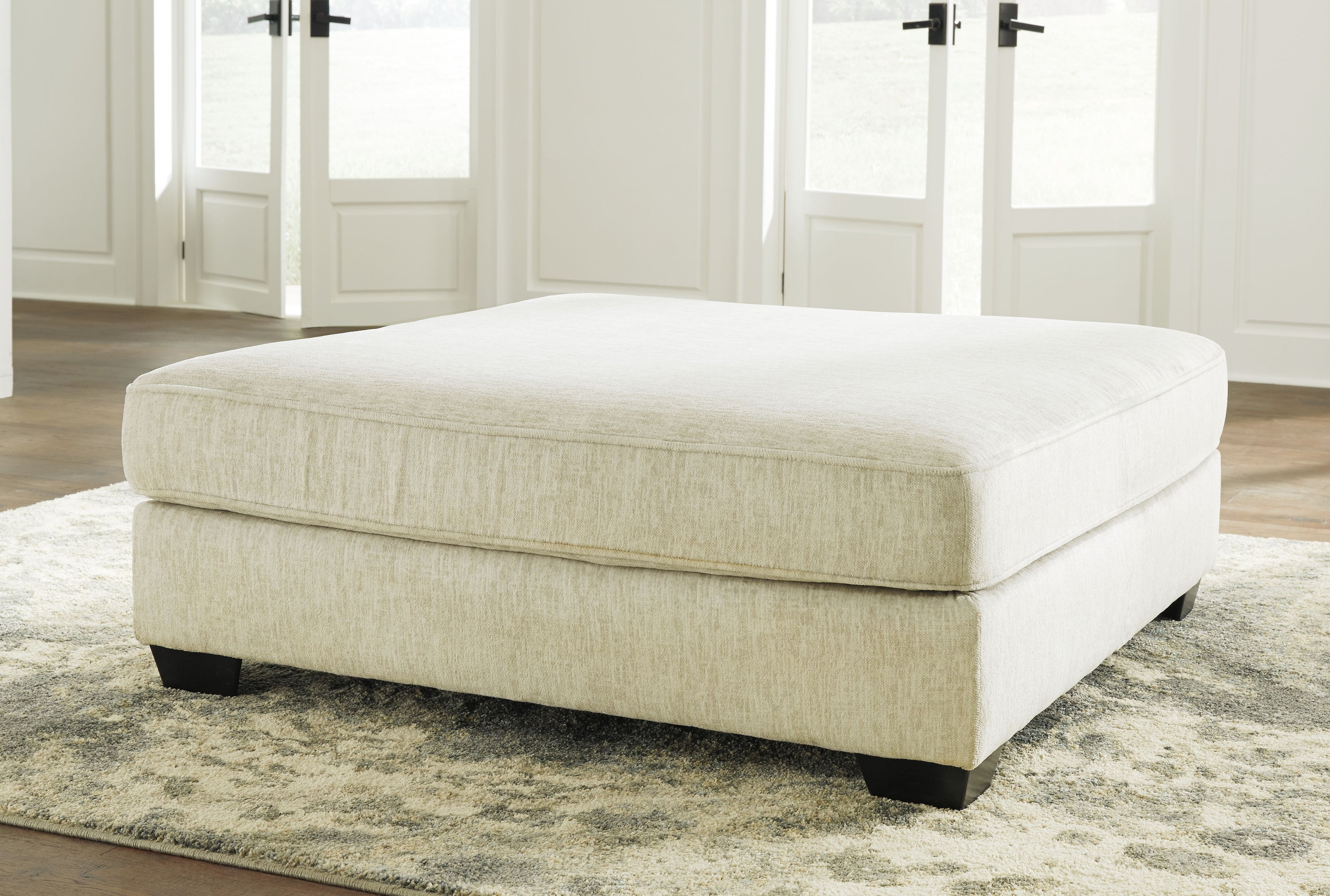 Parchment upholstered ottoman with square seat and dark base legs
