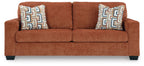 Spice rust sofa sleeper with two patterned throw pillows, centered front view.
