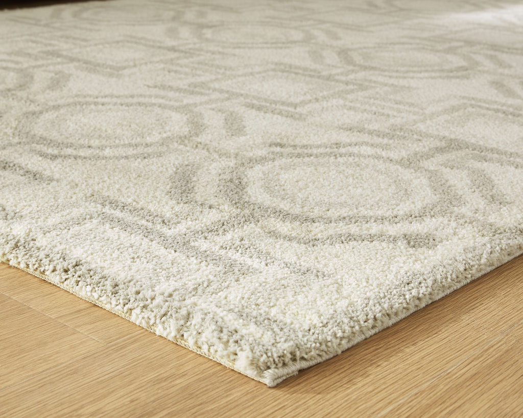 Beige area rug corner with textured low pile and geometric pattern