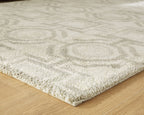 Beige area rug corner with textured low pile and geometric pattern