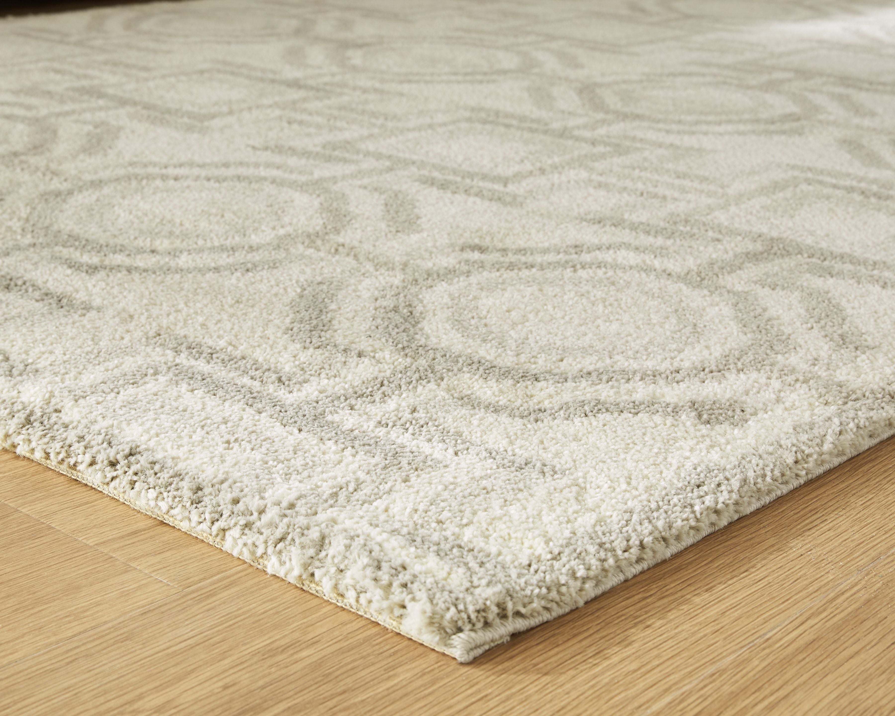 Beige area rug corner with textured low pile and geometric pattern