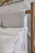 Upholstered bed frame with grey fabric headboard and dark brown legs, side view