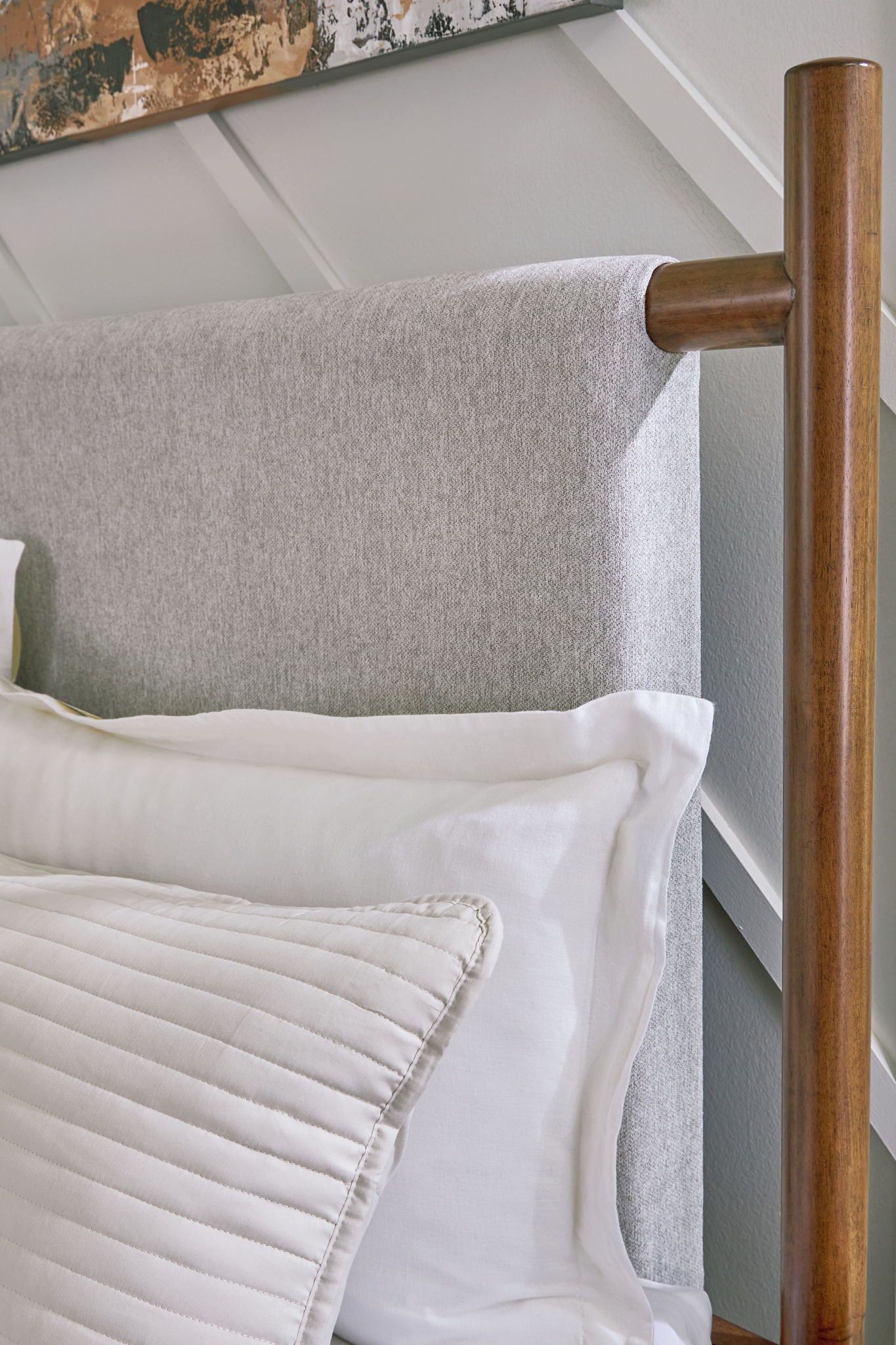 Upholstered bed frame with grey fabric headboard and dark brown legs, side view
