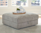 Pebble gray upholstered storage ottoman with rounded top and hinged lid