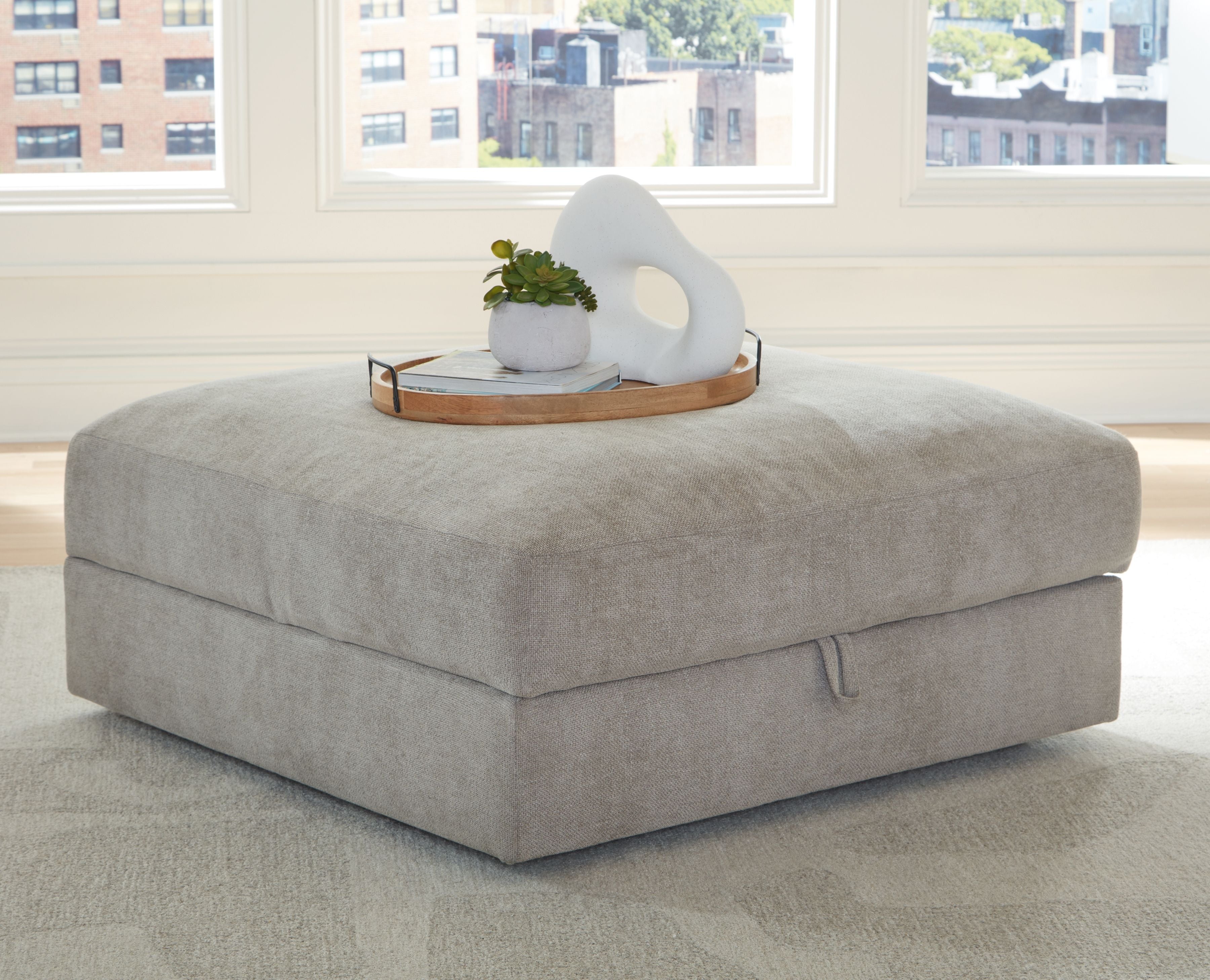 Pebble gray upholstered storage ottoman with rounded top and hinged lid