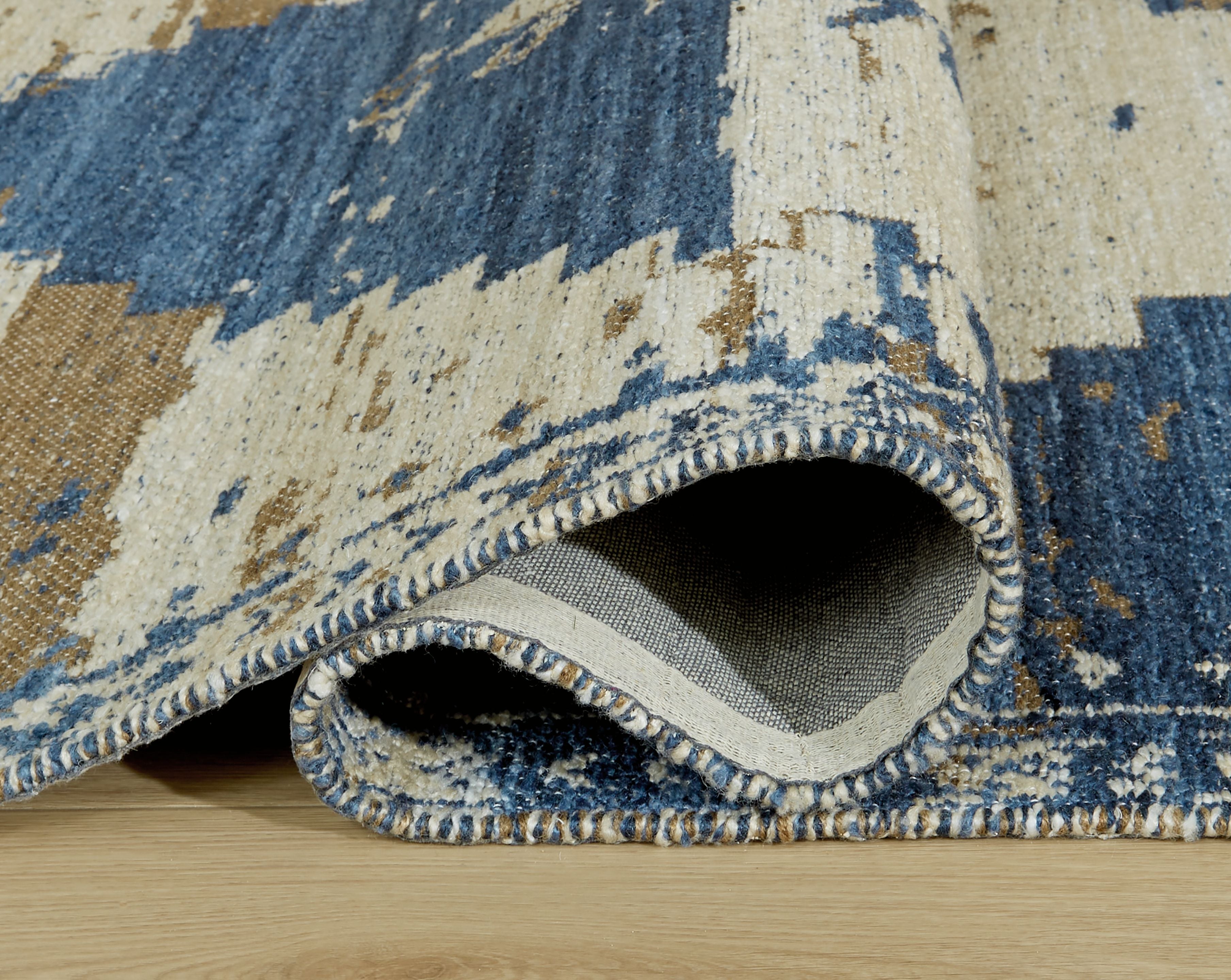 Blue and cream rug edge with decorative trim and visible woven underside