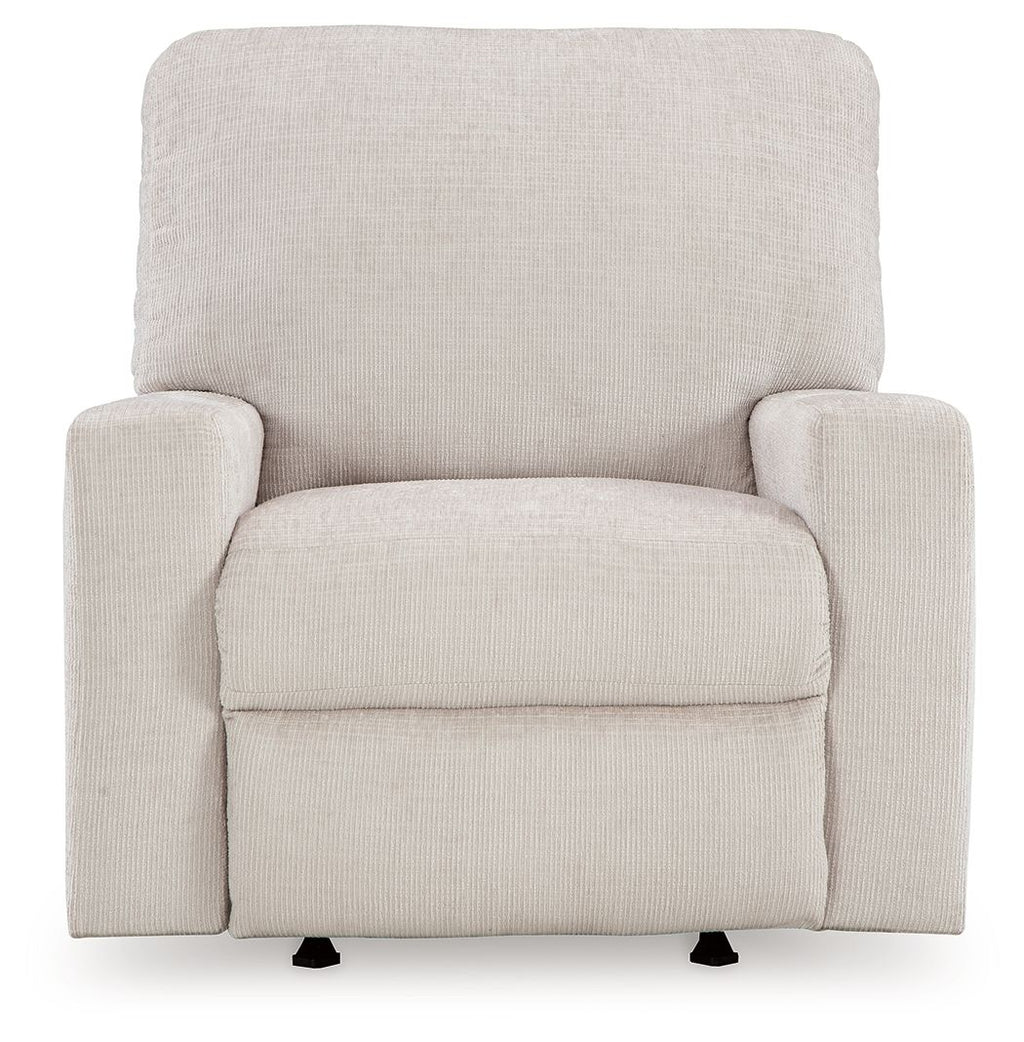 Rocker recliner chair in light beige upholstered fabric with front armrests and seat pad.