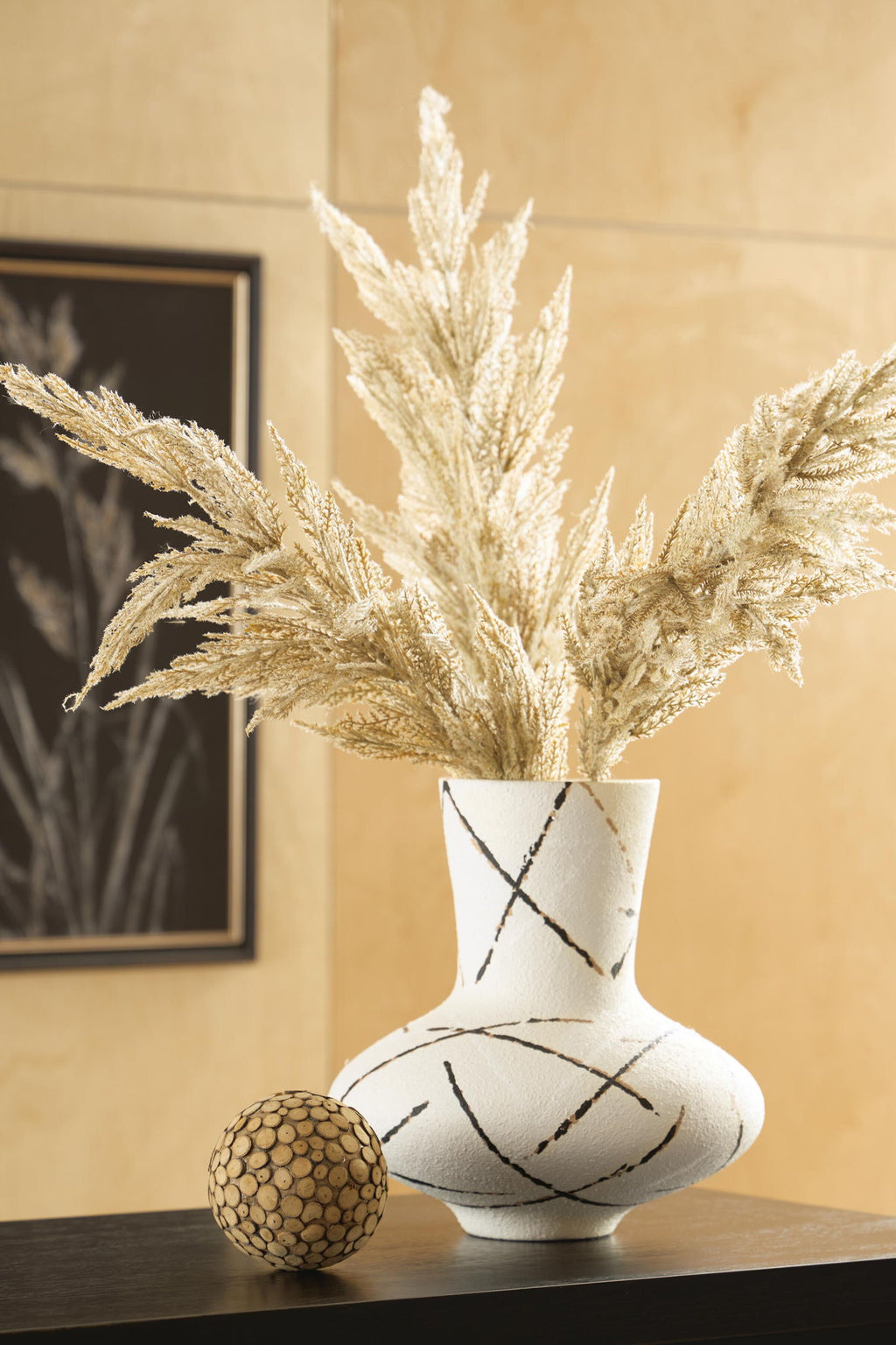 Cream vase holding dried pampas grass, black and brown crisscross line pattern.