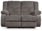 Gray reclining loveseat with padded arms, split back cushions, and recline footrest