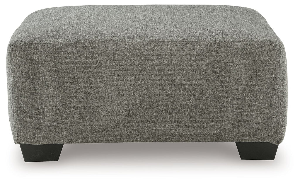 Boxy gray upholstered ottoman with dark legs and rounded top edge