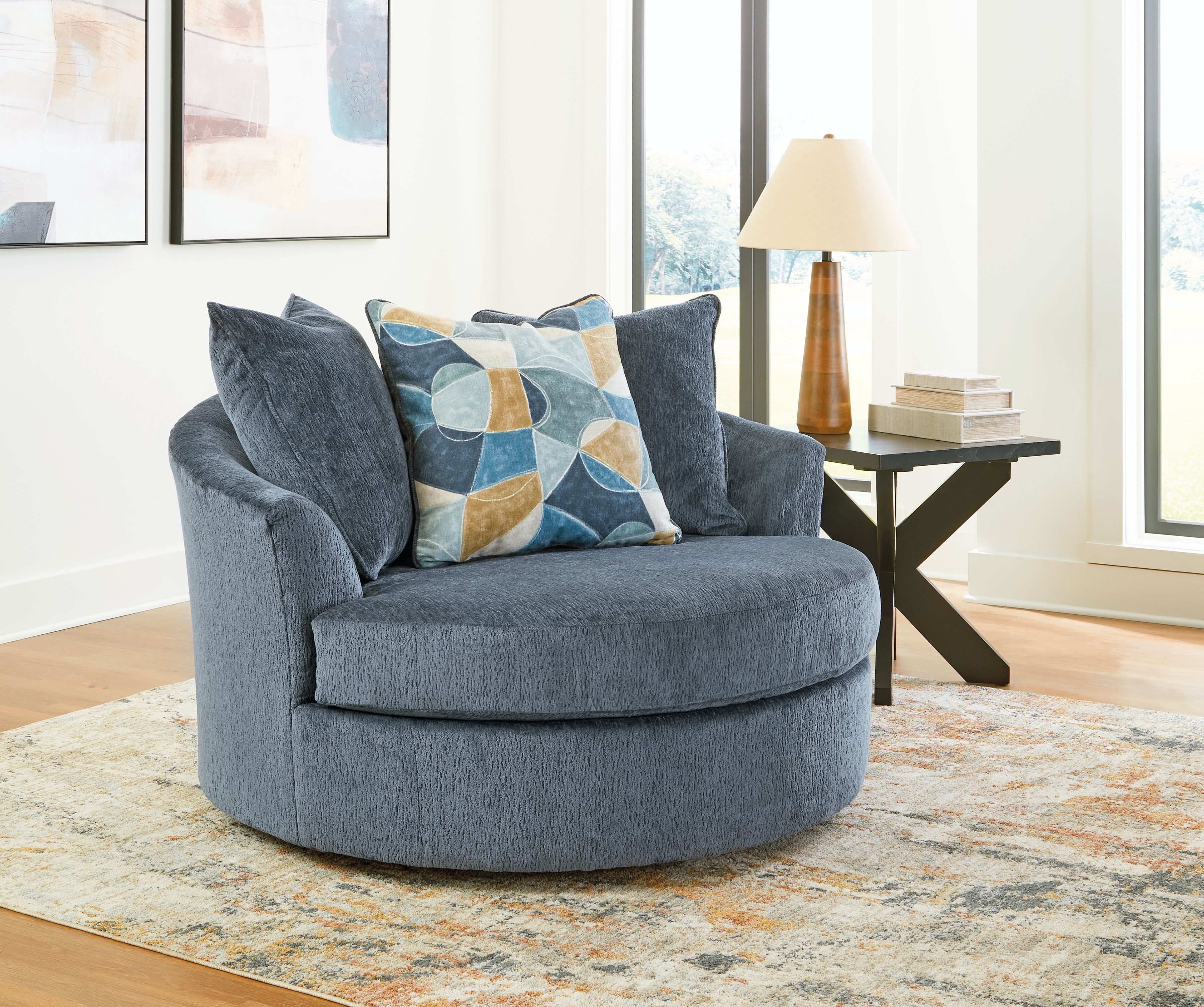 Dark blue oversized swivel accent chair with patterned throw pillow