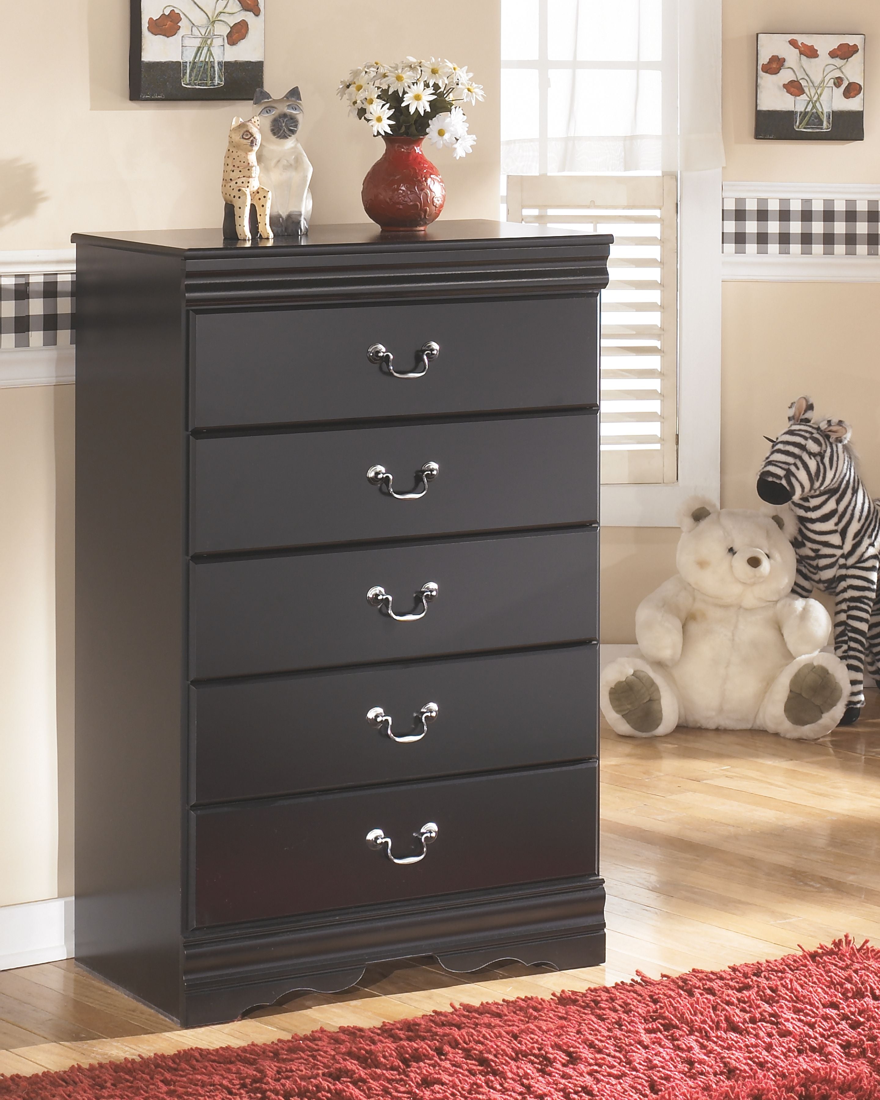 Black five-drawer chest, front view, with five metal knob pulls and scalloped base.