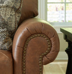 Caramel leather sofa arm with studded trim and patterned throw cushion