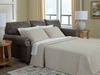 Queen sofa sleeper with pull-out bed and light plaid bedding on dark umber upholstery
