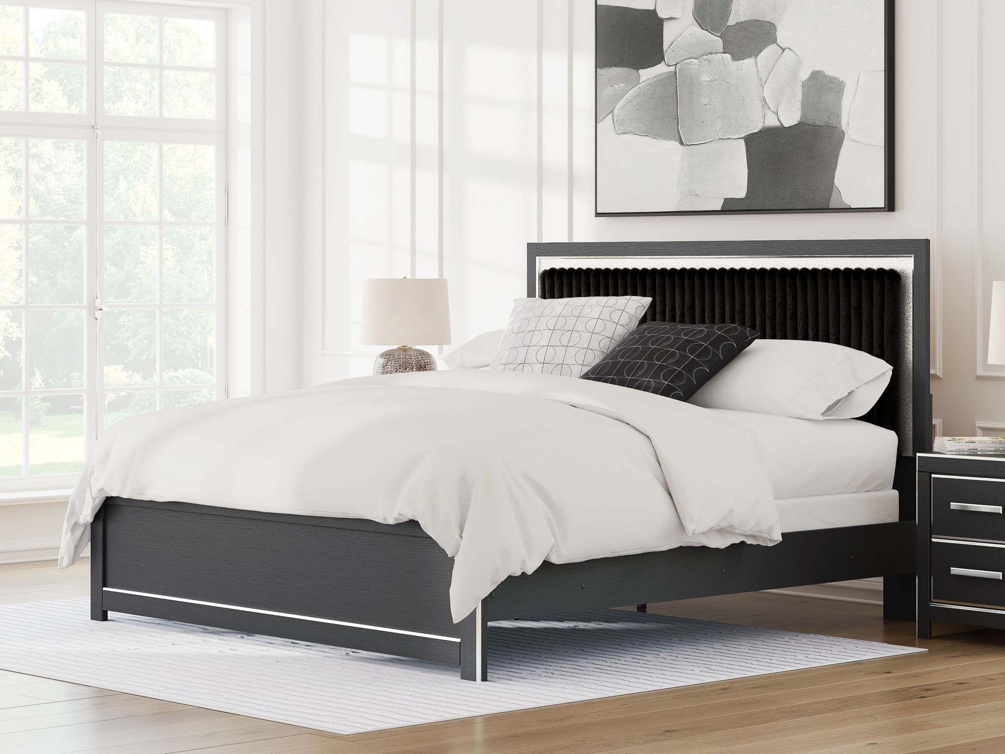 Upholstered panel bed with black headboard and white duvet, with stacked pillows