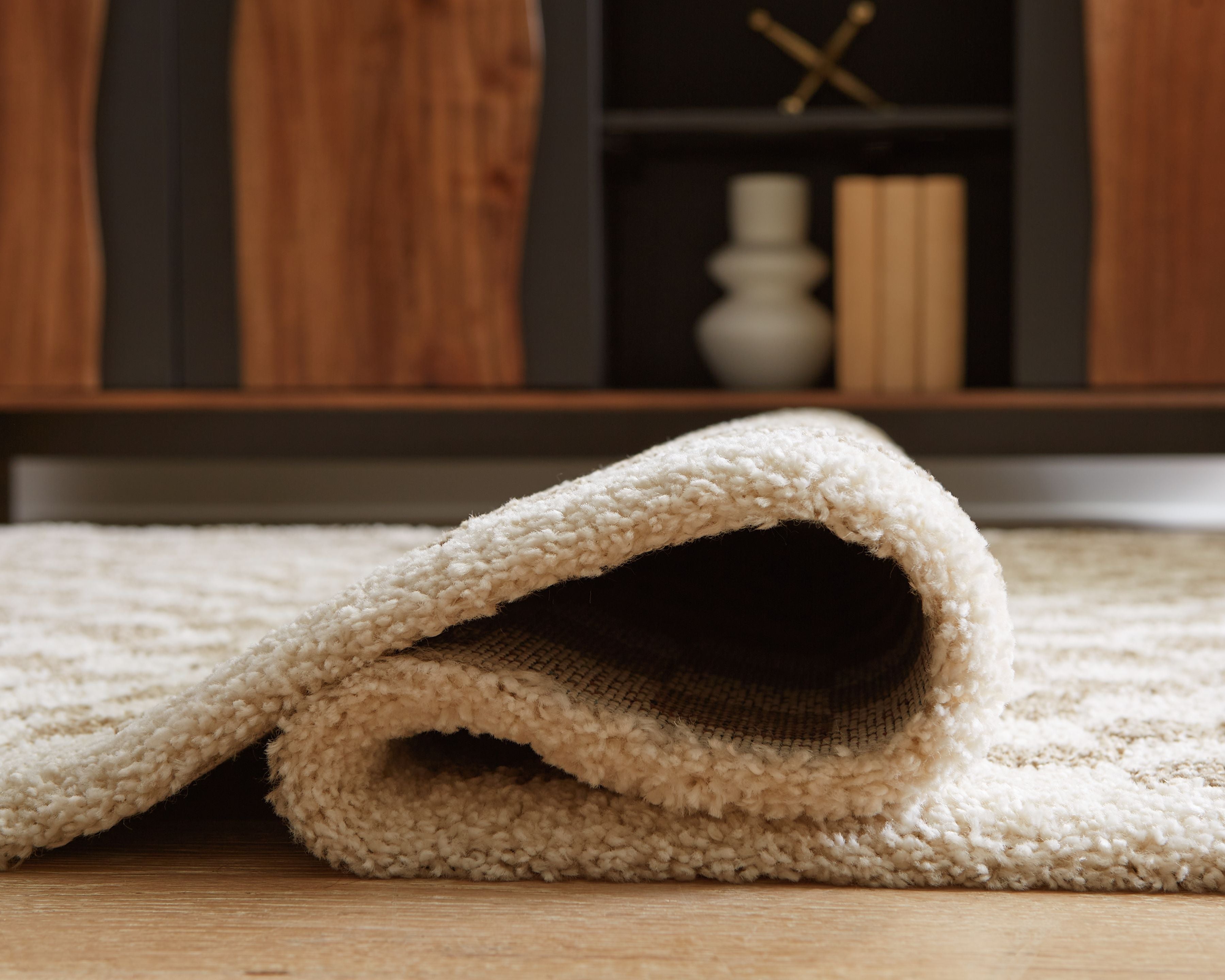 Beige rug edge rolled up, showing low-pile backing
