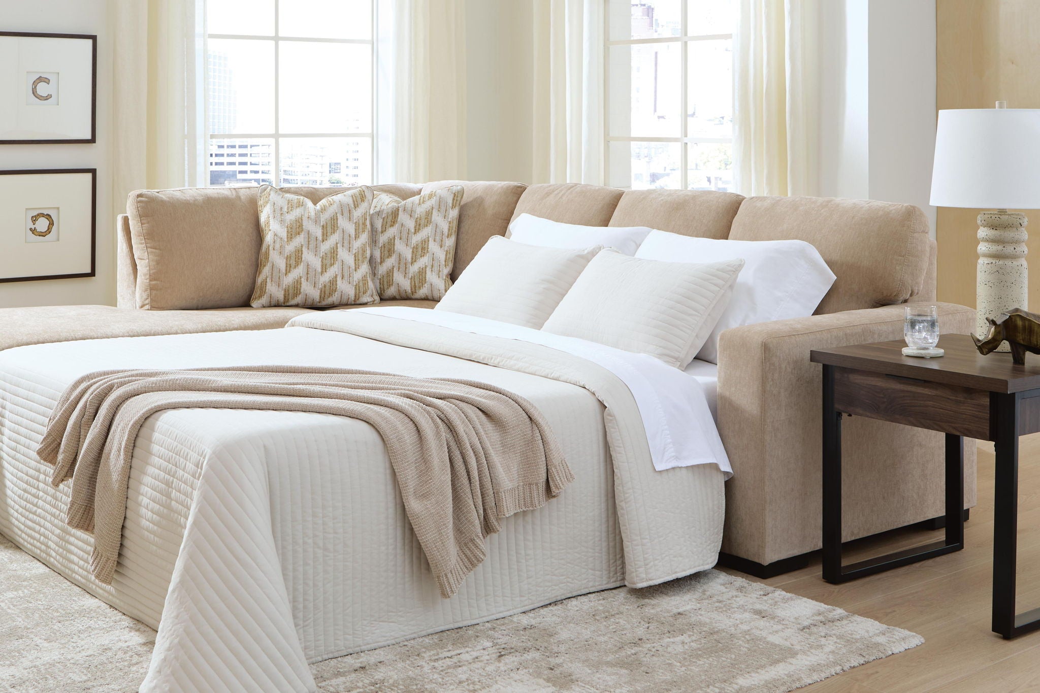 Light brown sleeper sectional with open bed platform, white bedding, and corner cushions