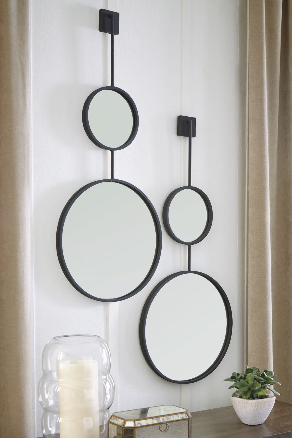 Wall-mounted mirror set with three oval mirrors on black bar frames.