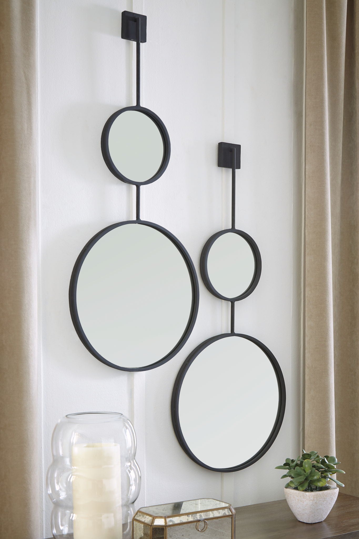 Wall-mounted mirror set with three oval mirrors on black bar frames.