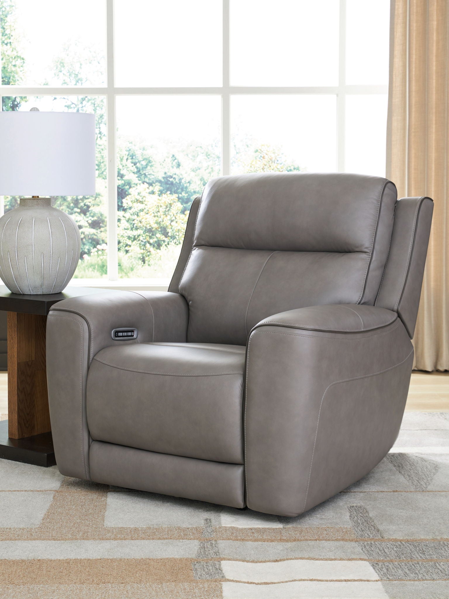 Gray power recliner with adjustable headrest and arm control panel.