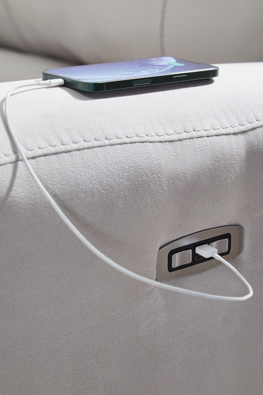 Light gray sofa armrest with charging port and connected cable