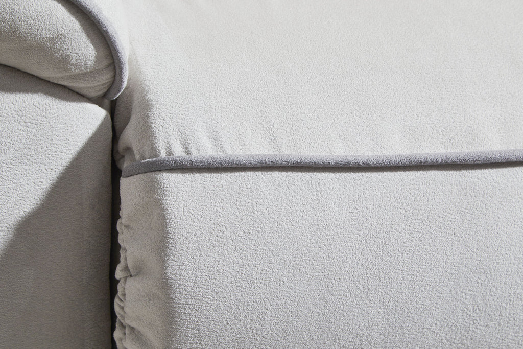 Light gray sofa arm and armrest seam with textured upholstery
