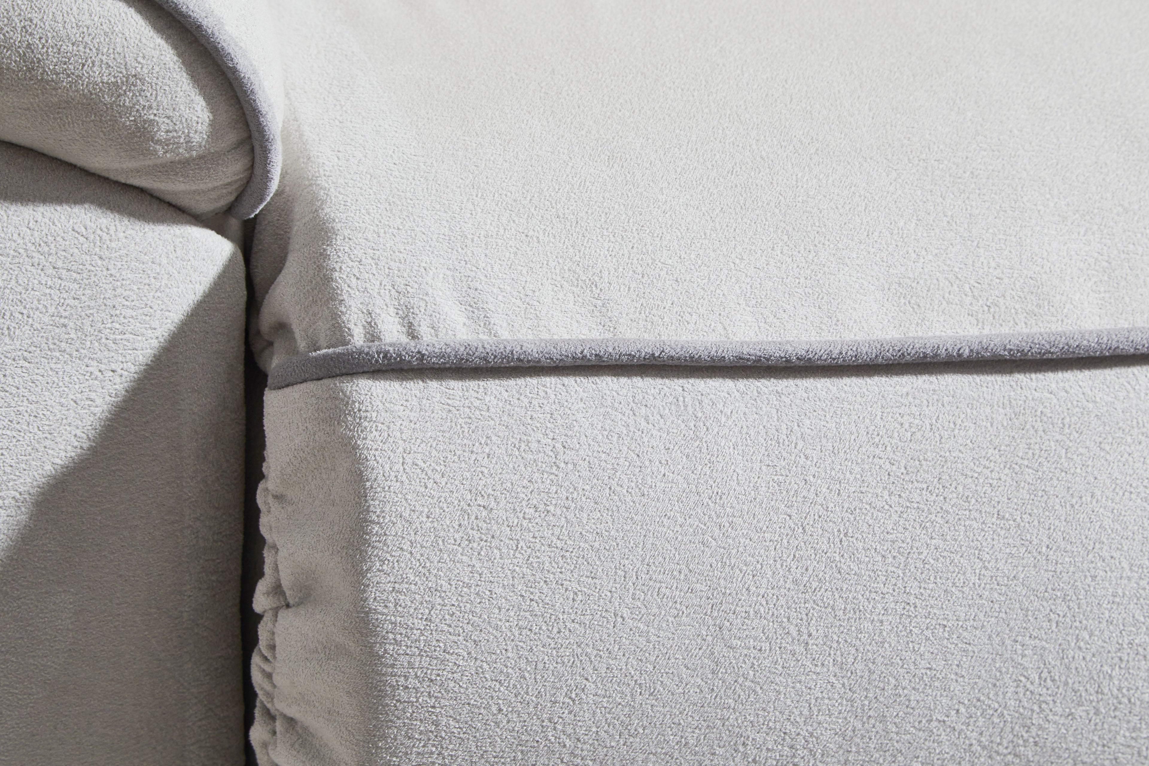 Light gray sofa arm and armrest seam with textured upholstery