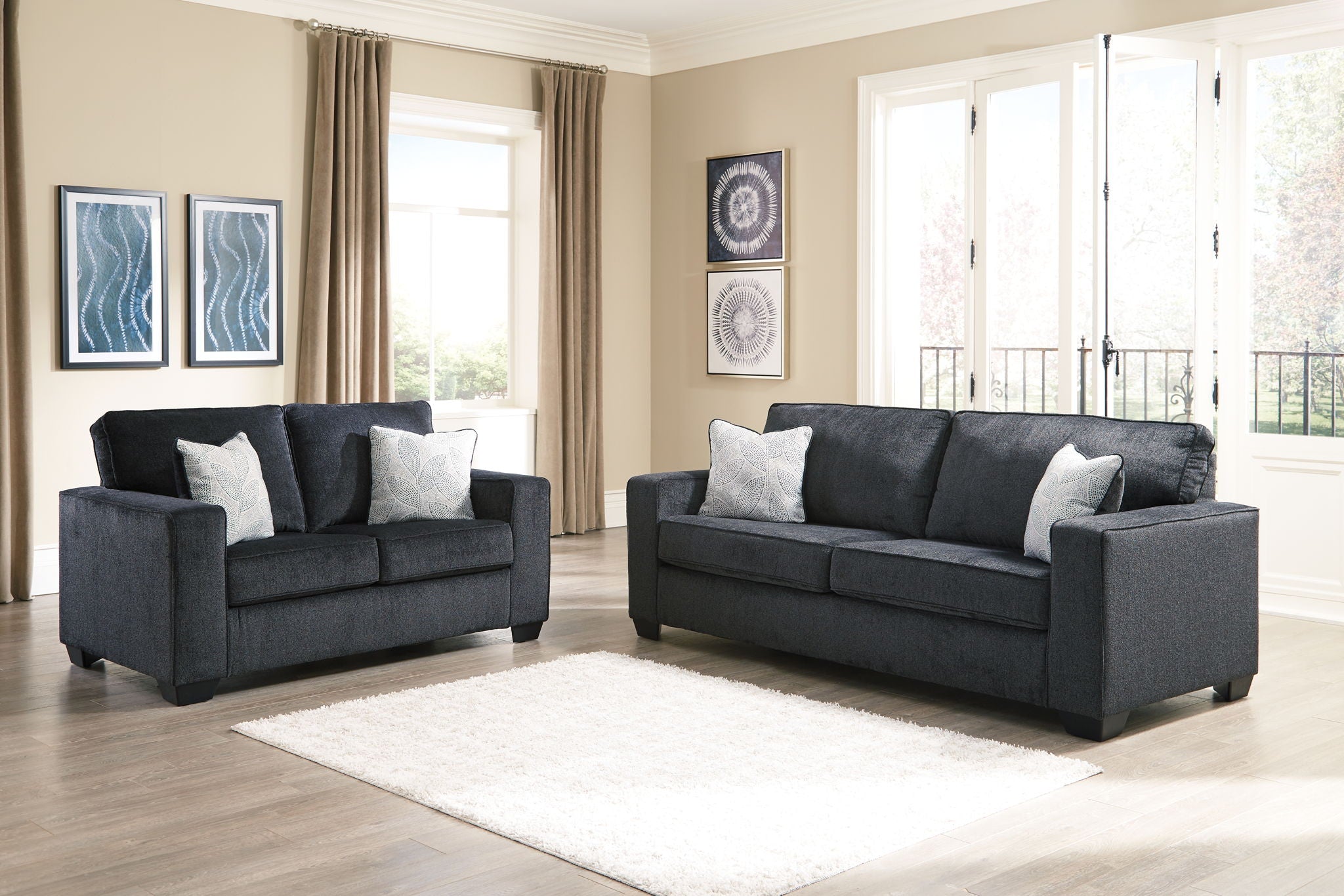 Dark gray loveseat with two gray-and-white patterned throw pillows and squared arms