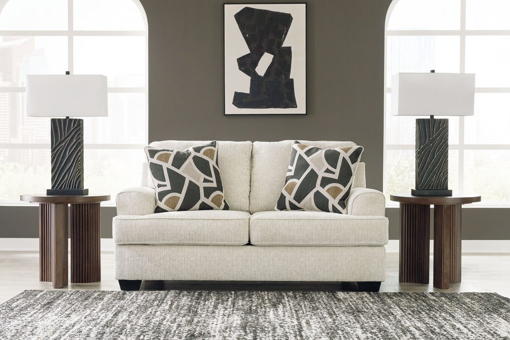 Light beige loveseat with two geometric black-and-beige throw pillows and dark tapered legs