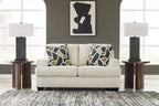 Light beige loveseat with two geometric black-and-beige throw pillows and dark tapered legs