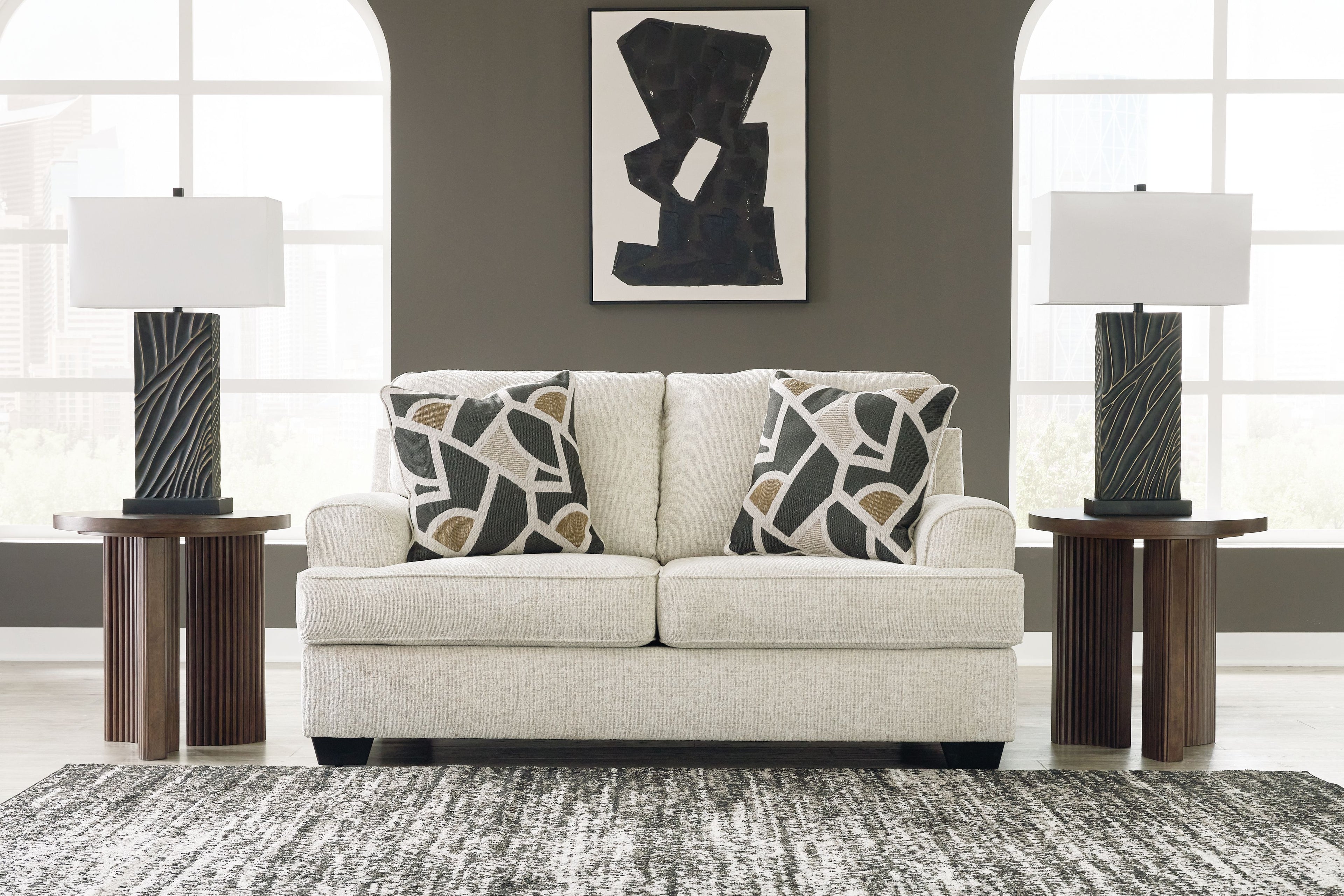 Light beige loveseat with two geometric black-and-beige throw pillows and dark tapered legs
