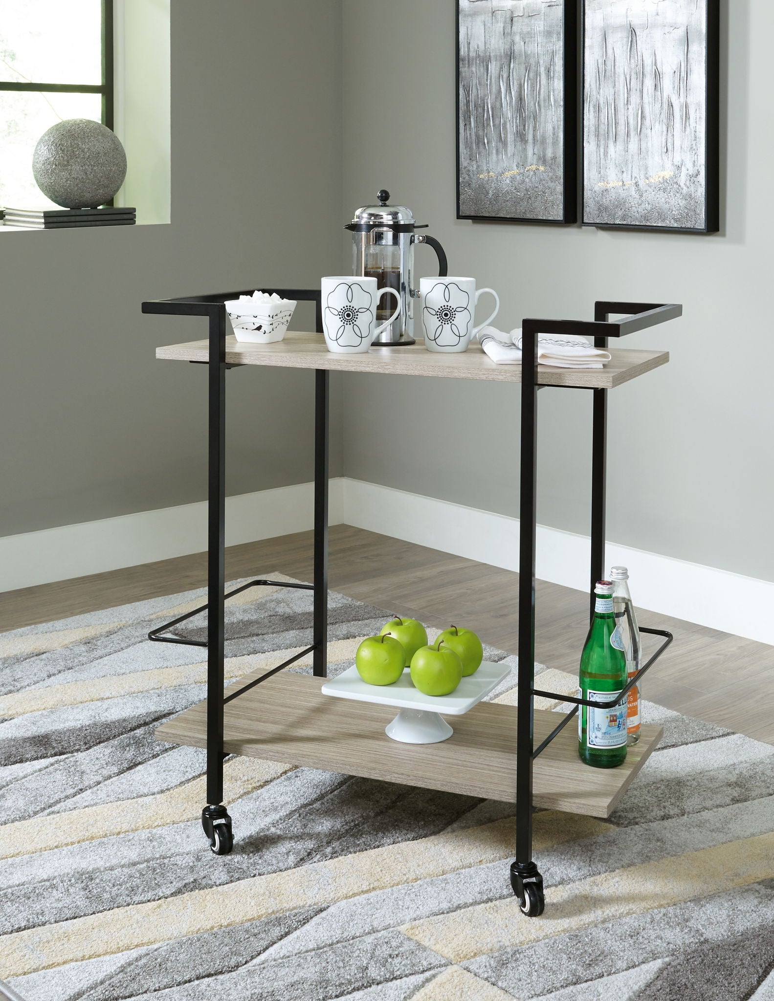 Bar cart with dark metal frame, light wood top and shelves, wheeled base