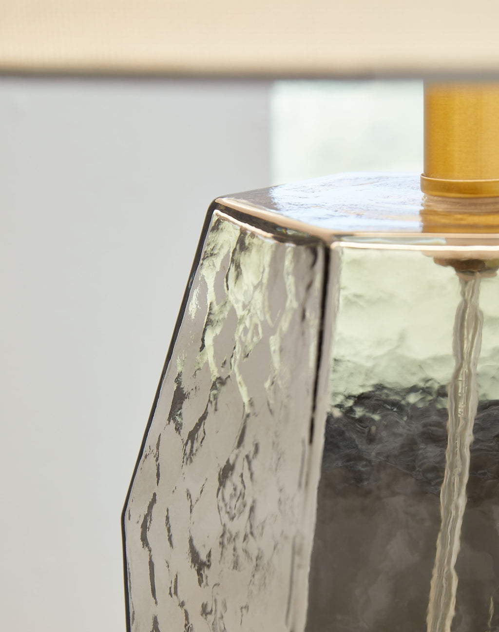 Glass lamp base close-up with faceted gray panels and gold collar