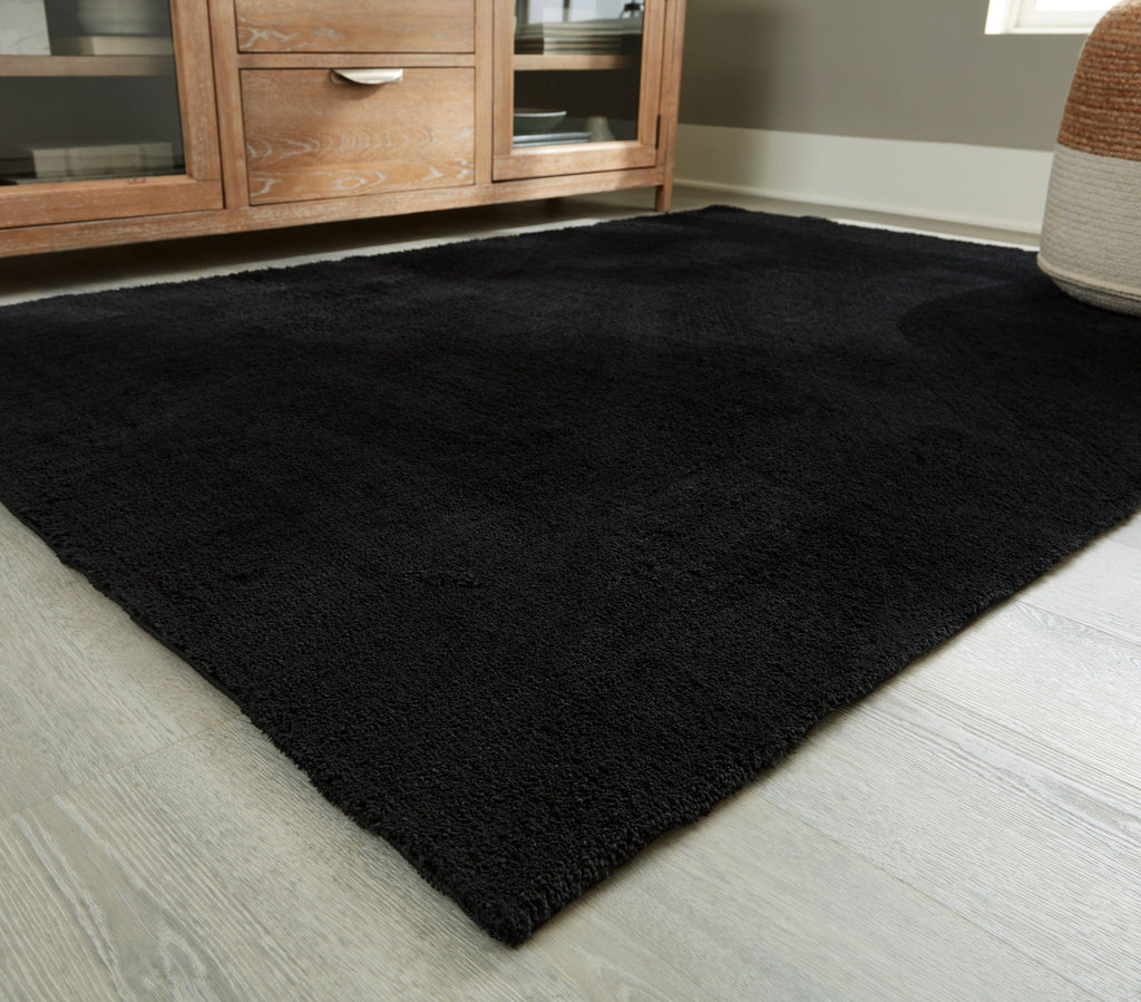 Anaben rug in black, low-pile texture, laid in living room corner