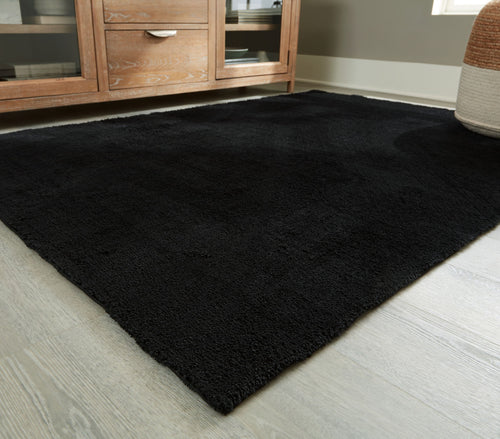 Anaben rug in black, low-pile texture, laid in living room corner