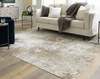 Light brown distressed area rug under living room sofa, short pile