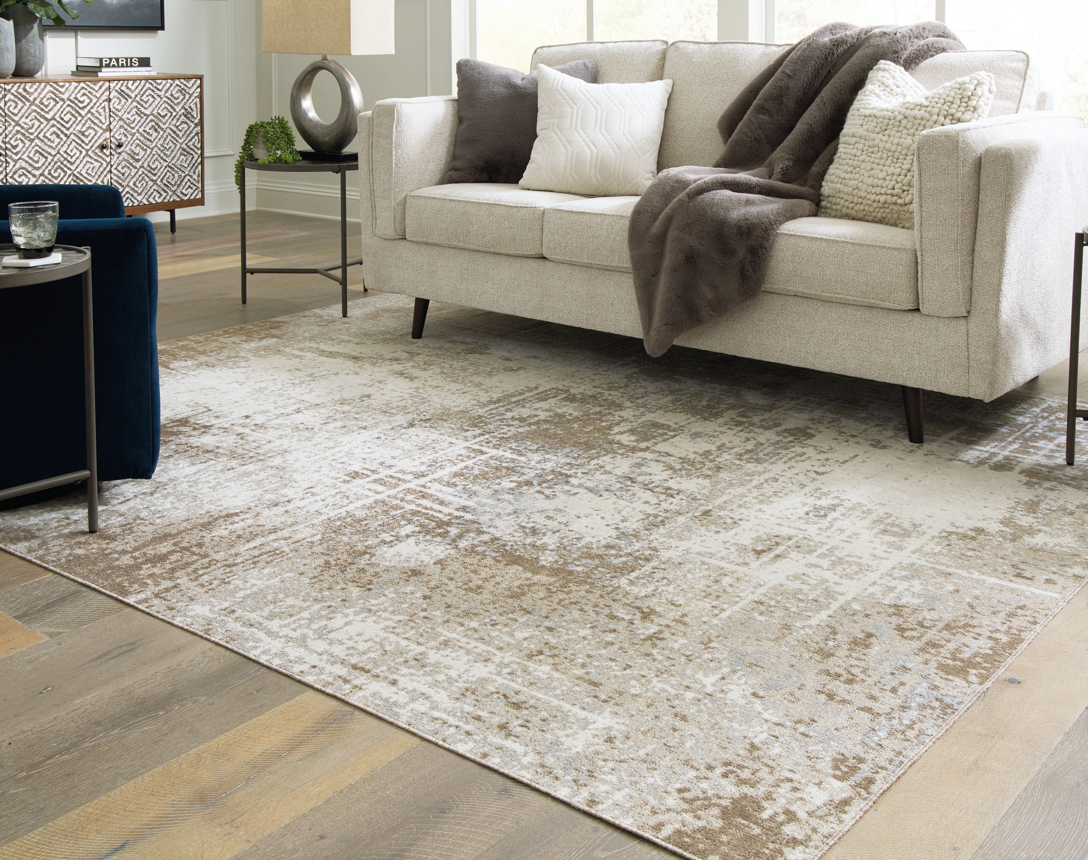 Light brown distressed area rug under living room sofa, short pile