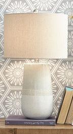 Beige fabric table lamp shade over speckled ceramic base with band detail