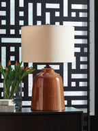 Rust glass table lamp with beige fabric shade, shown on a console