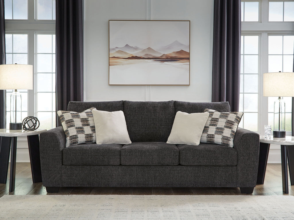Gray upholstered sofa with patterned and white accent pillows