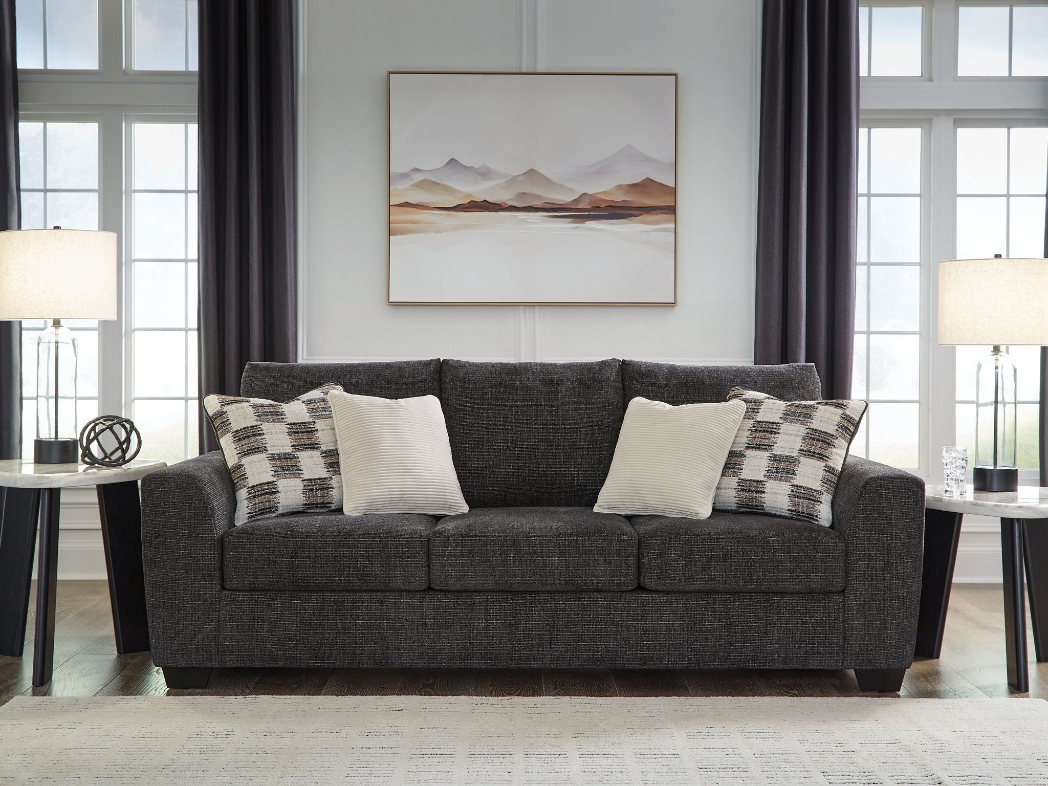 Gray upholstered sofa with patterned and white accent pillows
