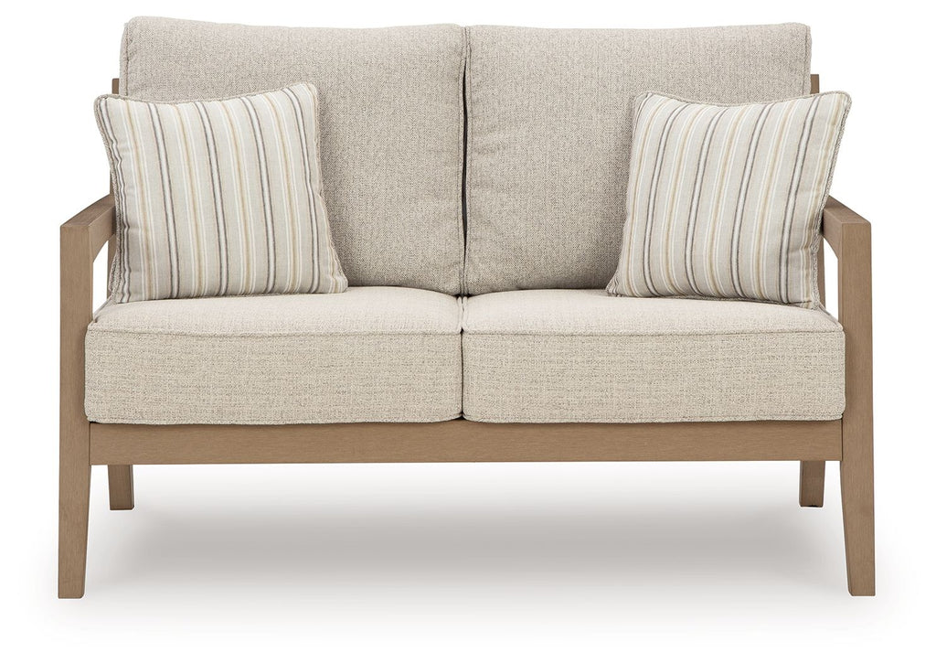 Beige loveseat with cushioned seats and two striped throw pillows, driftwood legs