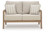 Beige loveseat with cushioned seats and two striped throw pillows, driftwood legs