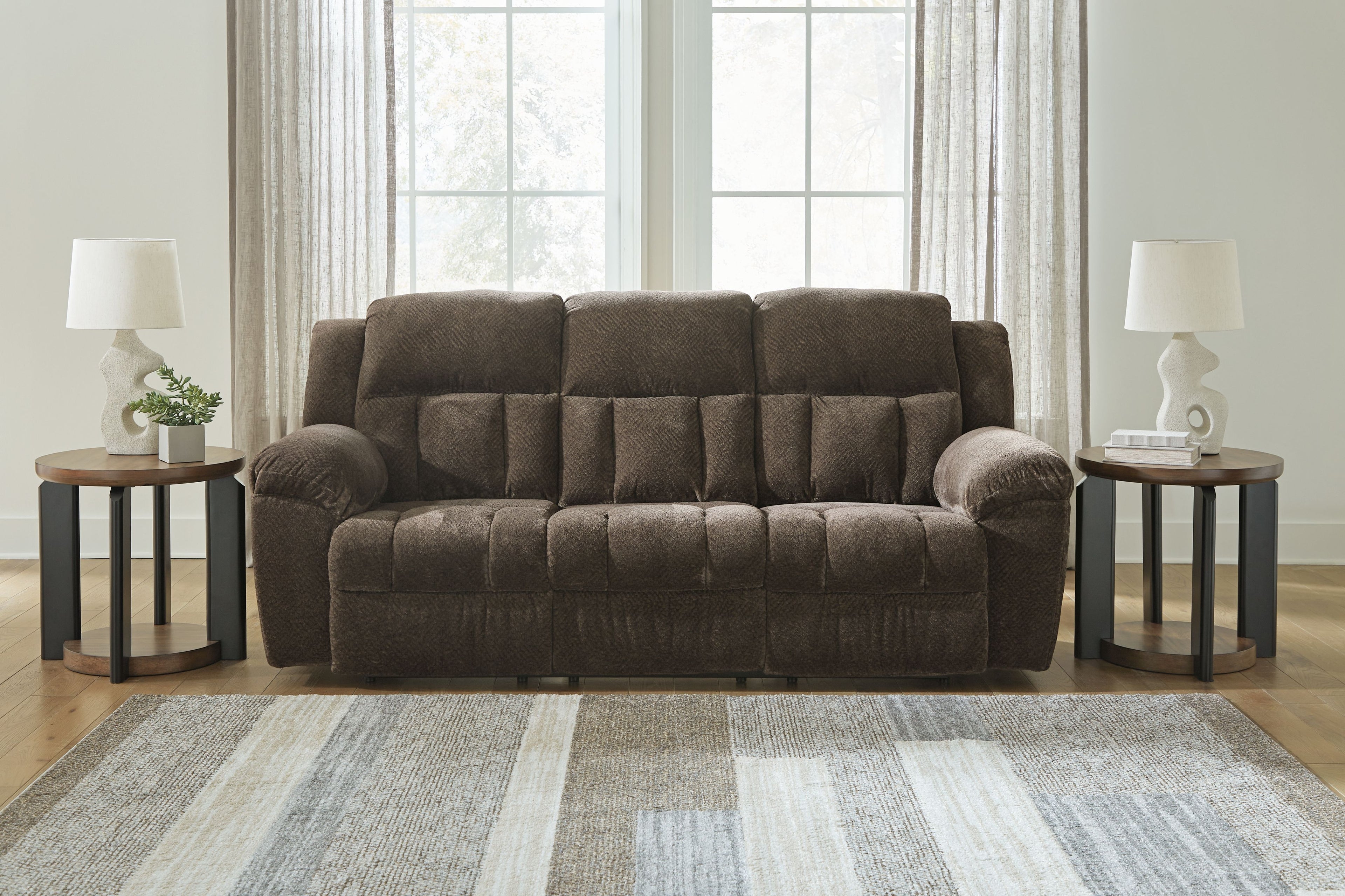Dark brown reclining sofa with tufted back panels, rounded arms, and cushioned seat